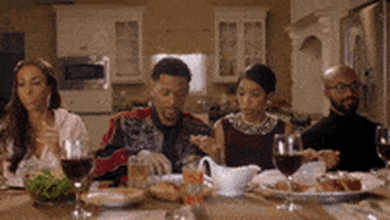 TV gif. Vince Swann, Kiya Roberts, Jasmin Brown, Tristen Winger, and Mark Harley in 50 Central sitting at a table for Thanksgiving with their heads bowed in prayer.
