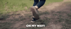 Video gif. A shot of a person's feet wearing running shoes jogging on unpaved ground. Text, "On my way!"