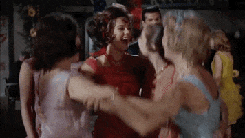 Movie gif. Group of women, including Natalie Wood as Deanie in Splendor in the Grass, link arms in a circle and jump for joy.