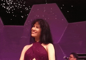 Celebrity gif. Smiling on stage, Selena gives the crowd a thumbs up.