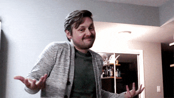 Video gif. Bearded man shrugs as he tilts his head with a sheepish smile.
