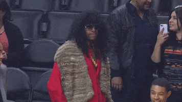 Sports gif. Paul Pierce in a Rick James costume turns and smiles. A basketball bounces up and down in the foreground.