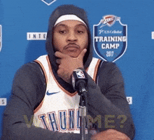Sports gif. Wearing an Oklahoma City Thunder jersey, Carmelo Anthony looks confused and asks, “Who me?” Then, he smiles and laughs.