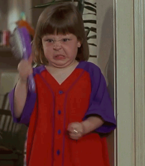 Gif of a very angry little girl snarling and waving a hair brush.