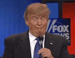 Political gif. Trump holds a dual microphone up to his face. He tightens his mouth into a line and blinks. A Fox News sign is behind him.
