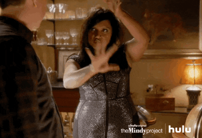 Mindy Lahiri from tv show the Mindy Project making gestures to symbolize performing magic in a fancy silver dress gif