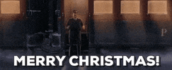 Cartoon gif. The conductor from Polar Express is standing on one of the train's platforms and he yells out, "Merry Christmas!" as the train slowly pulls away.