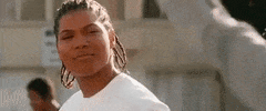 Movie gif. Queen Latifah as Cleo in Set it Off grins at a person before bursting into laughter.