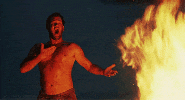 Movie gif. Tom Hanks as Chuck Noland in Cast Away sweaty and shirtless yells and gestures to a giant bonfire at night.