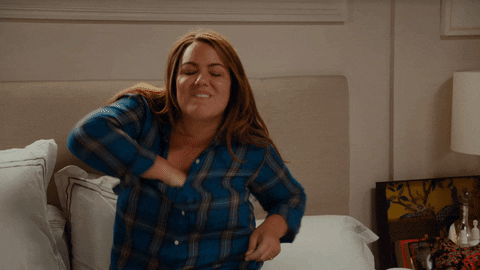 Gif of a woman pulling her bra out of her top and tossing it aside in relief.