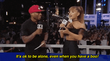 TV gif. Ariana Grande and Charlamagne talk into microphones outside the MTV Video Music awards where she gestures with her hand out and says, 'It's ok to be alone, even when you have a boo!"