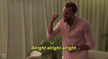 Reality TV gif. With a drink in hand, Robby Hayes from The Bachelorette wears a pink button up and pumps his fist in celebration while confidently repeating to himself, "Alright alright alright," which appears as text.