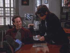 Seinfeld gif. Jerry sits with his feet on a table and a cigar in his mouth, smiling and nodding as Julia Louis-Dreyfus counts out cash in front of him, looking annoyed.