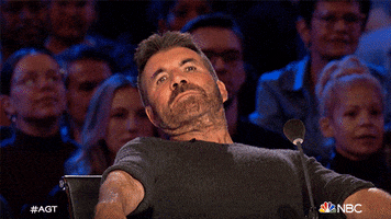 Reality TV gif. We zoom in on Simon Cowell on America's Got Talent as he leans way back and his eyes go wide.