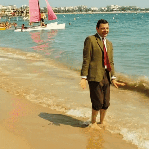 An animated gif of Mr. Bean on the beach in the waves. He loves it and then gets scared by a bigger wave.