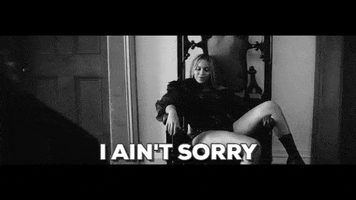 Music video gif. Beyoncé lounges in a throne-like chair with leg slung over the side in the black and white video for Sorry. She throws up a hand as she sings, "I ain't sorry," 