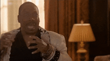 Movie gif. Eddie Murphy as Akeem in Coming 2 America plunges angrily with his hands out to choke Arsenio Hall as Semmi, who looks terrified and then gets tackled to the floor.