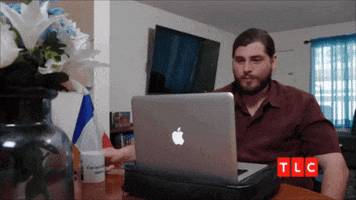 Reality TV gif. Andrew Kenton on 90 Day Fiancé sits in front of a laptop and waves toward it with a smile as he says, "Oh, hello."