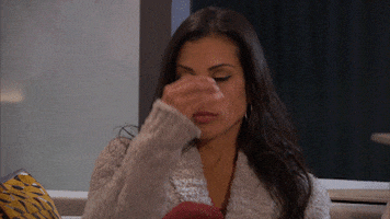 Reality TV gif. A woman on the Bachelor in a gray sweater pinches the bridge of her nose in frustration.