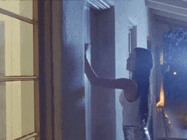 Music video gif. Olivia Rodrigo in "Good 4 U" angrily bangs on a front door with her fist then cranes her neck forward to look through its window. 