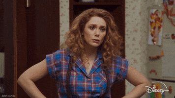Marvel gif. Elizabeth Olsen as Wanda stands in the kitchen wearing a red and blue flannel shirt with brown suspenders. Her head drops inwards as she furrows her eyebrows in confusion.