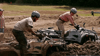 Two people riding ATVs that are stuck in mud