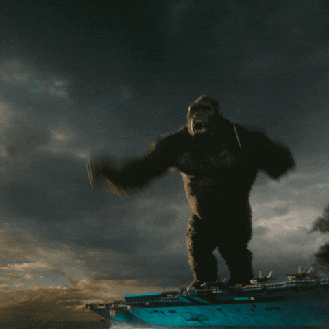 Movie gif. In slow motion, King Kong in Godzilla vs. Kong jumps off of an aircraft carrier with his arms up in the air. As he jumps, the ship explodes with a large blue flame erupting out from the blast and into the sky. Text flies on screen next to King Kong that says, “Leaving work for the weekend.” 