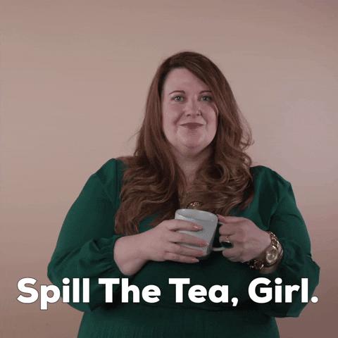 Reaction gif. A non-apparently Disabled white woman with with anxiety and depression and long red hair holds a mug, saying "Spill the tea girl," punctuating with a sip.
