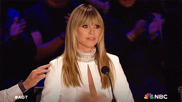 Reality TV gif. Heidi Klum on America's Got Talent sits at the judge's table and raises her hand in a sassy motion and holds her palm up to the other judges as if to say, "Let me stop you right there."