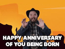 Celebrity gif. Howdy Price, dressed in a plaid flannel, denim jacket, and black cowboy hat, smiles and holds his hands out toward us, saying, "Happy anniversary of you being born," which appears as text.