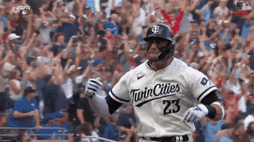Sports gif. Royce Lewis of the Minnesota Twins is ecstatic as he does an energetic side skip in slow motion and gestures at the crowd, rubbing his fingers together like, "That was money." 