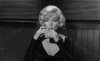 Movie gif. Marilyn Monroe as Sugar Kane in "Some Like It Hot," lazily closes her eyelids as she tips her head back to drink from a flask.