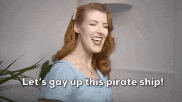 Video gif. Youtuber Jessica Kellgren-Fozard grins broadly at us and gives us a thumbs up while she says, "Let's gay up this pirate ship!"