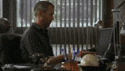 TV gif. Hugh Laurie as Dr. Gregory from House sits at a cluttered desk and acts like he's busy by clacking on his computer, which isn't even turned on. He looks up nonchalantly.