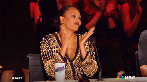Reality TV gif. Mel B on America's Got Talent. She's sitting at the judges table and she slow claps and curls her top lip up like she's impressed.