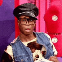 Reality TV gif. Queen out of costume on RuPaul's Drag Race looks out of his large glasses with wide eyes and his mouth open in shock.