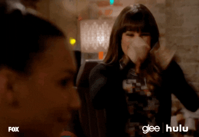 TV gif. Lea Michele as Rachel Berry on Glee jumps up, pumping her fists, as she screams in excitement. Naya Rivera as Santana Lopez turns to face Rachel. 