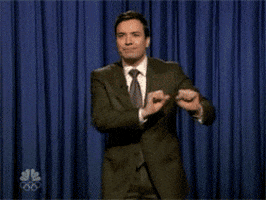 Tonight Show gif. Jimmy stands in front of the blue curtain doing the cabbage patch dance.