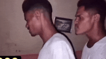 Video gif. Two men with identical white shirts and hairstyles simultaneously bob their heads back and forth in complete unison. Their faces show intense focus. 