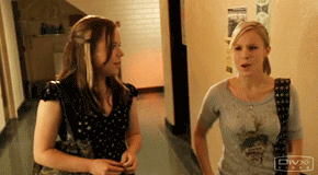 TV gif. Kristen Bell as Veronica Mars walks through a hallway with Tina Majorino as Mac and gives her a proud high-five.