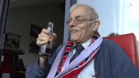 Video gif. An old man holding a drink bobs around with a smile, then mockingly pretends to begin dancing.