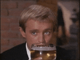 TV gif. David McCallum as Illya Kuryakin on The Man from Uncle raises a glass of beer to his mouth and takes a sip.