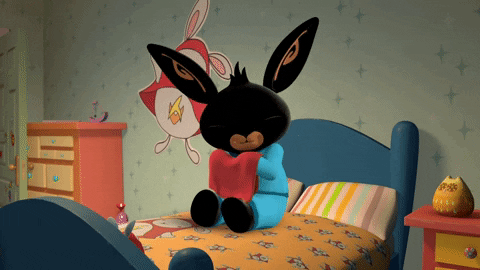 Cartoon gif. Bing Bunny sits on his bed rubbing a red towel on his chin for comfort, closing and opening his eyes with a pleasant expression.
