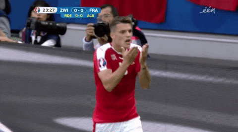 Sports gif. Granit Xhaka presses his palms together while walking forward and yelling with seriousness.