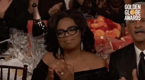 Celebrity gif. Oprah, seated at The Golden Globes, surrounded by applause, presses her hands together in thanks, and tips her head with humble pride. 