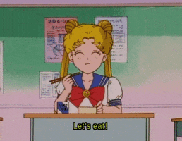 Anime gif. Sailor Moon sits at a desk holding chopsticks and chewing happily with her eyes closed. Text, "Let's eat!"