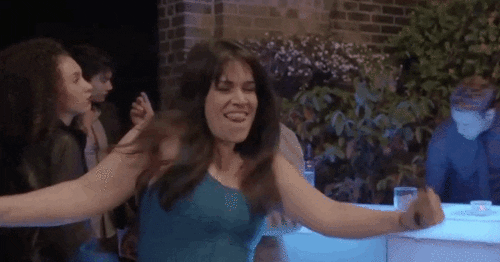 TV gif. Abbi Jacobson as Abbi Abrams on Broad City dances awkwardly in a nightclub. She shakes her arms close to her body and has a silly smile on her face, almost like a toddler dancing.