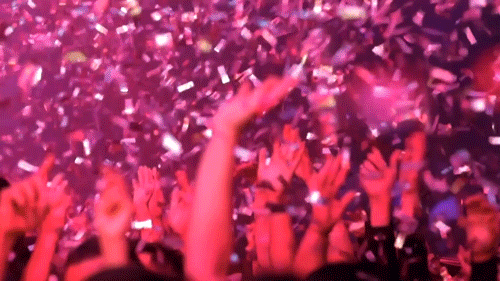 Gif k svátku s detaily na zdvižené ruce davu chytajícího padající konfety.