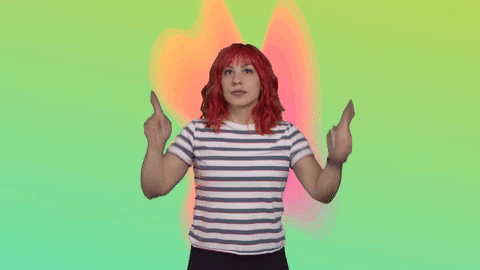 Video gif. Woman points his fingers up and shakes her hips, dancing a little.