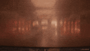 Trailer gif. A scene from the trailer of "Deadpool & Wolverine" shows an elevator door opening at the Time Variance Authority, revealing a masked Ryan Reynolds as Deadpool effortlessly rising from a full split with just his legs. 